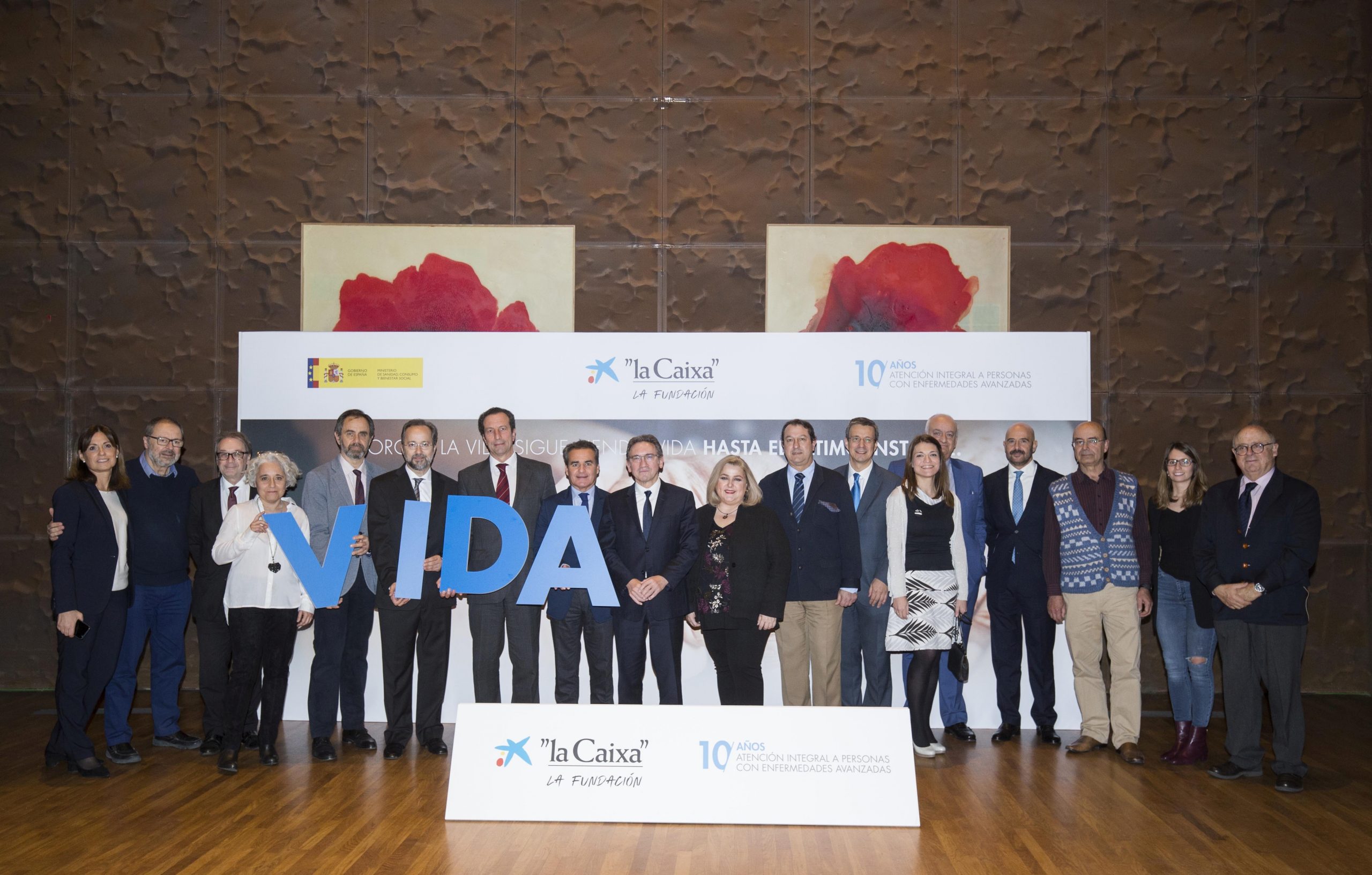 Un grupo de personas con traje sostiene letras azules que forman VIDA, junto a pancartas