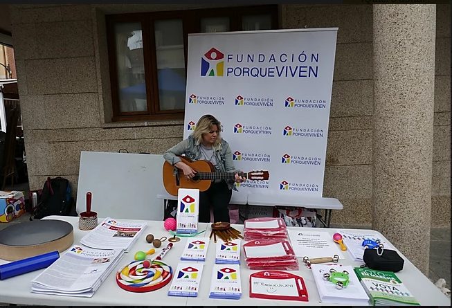 Una profesional de la Fundación porqueViven- en Madrid toca la guitarra junto a material informativo y recursos lúdicos