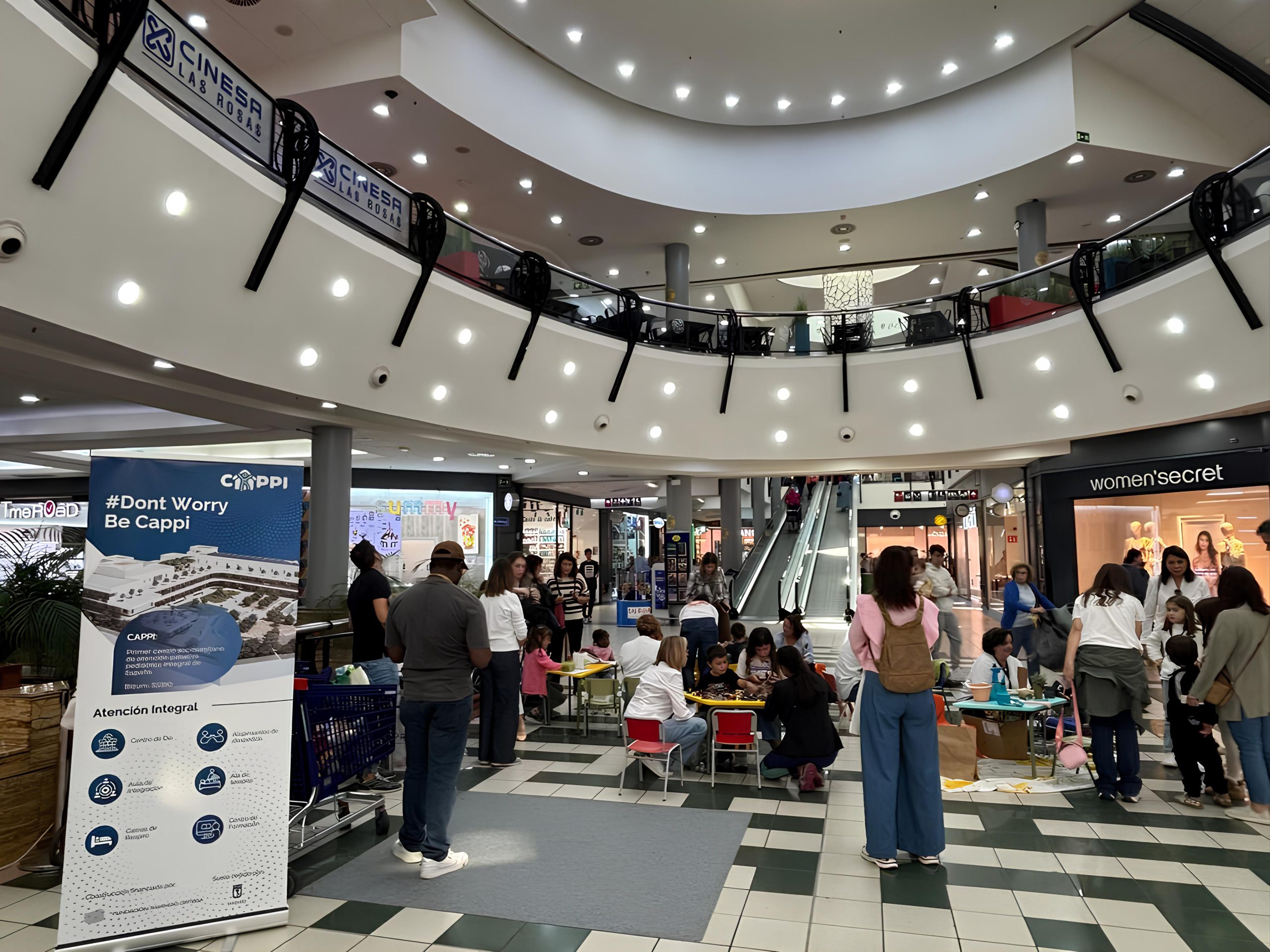 Familias y niños se reúnen en el atrio de un centro comercial de Madrid junto al banner Fundación porqueViven
